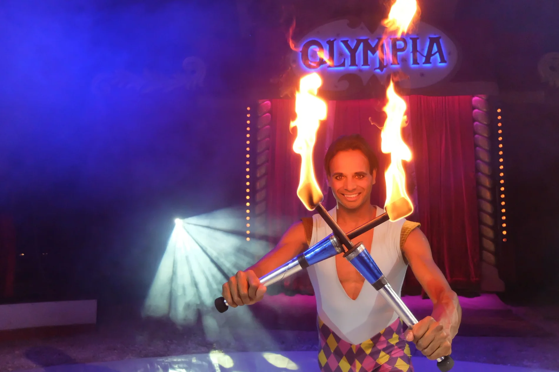 David Hammarberg håller två brinnande facklor i kors framför Cirkus Olympias upplysta entré