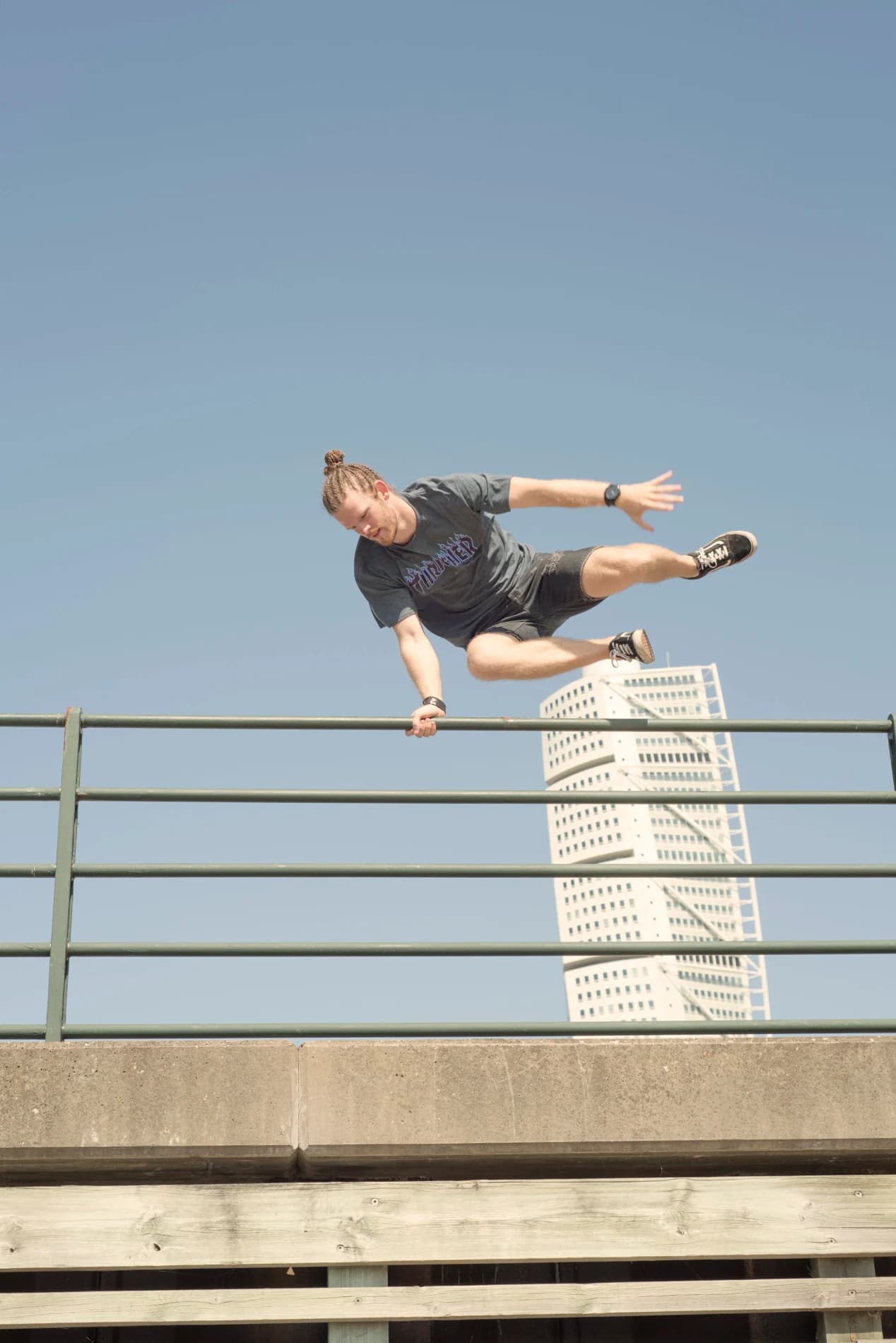 Emanuel Hansson hoppar över ett räcke i ett parkourtrick med Turning Torso i bakgrunden