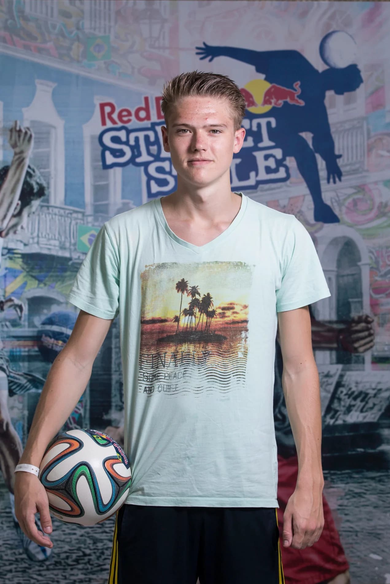 Emil Källdoff håller en fotboll under armen framför en Red Bull Street Style-fond