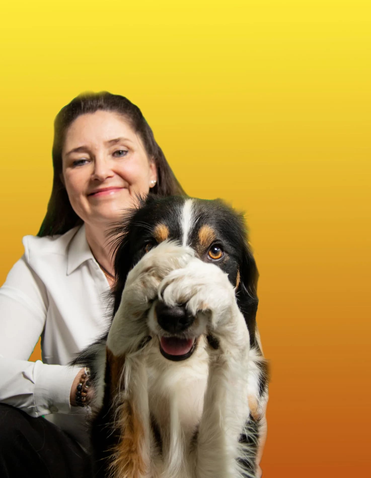 Hunden Lotus håller tassen över nosen framför en leende Lizette mot gulorange bakgrund