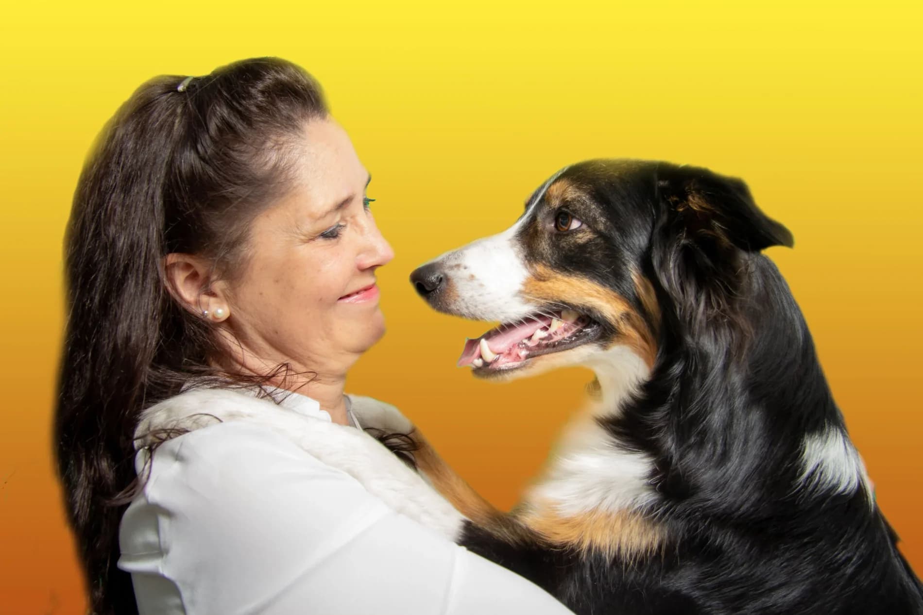 Lizette och hunden Lotus tittar på varandra i profil mot gulorange bakgrund