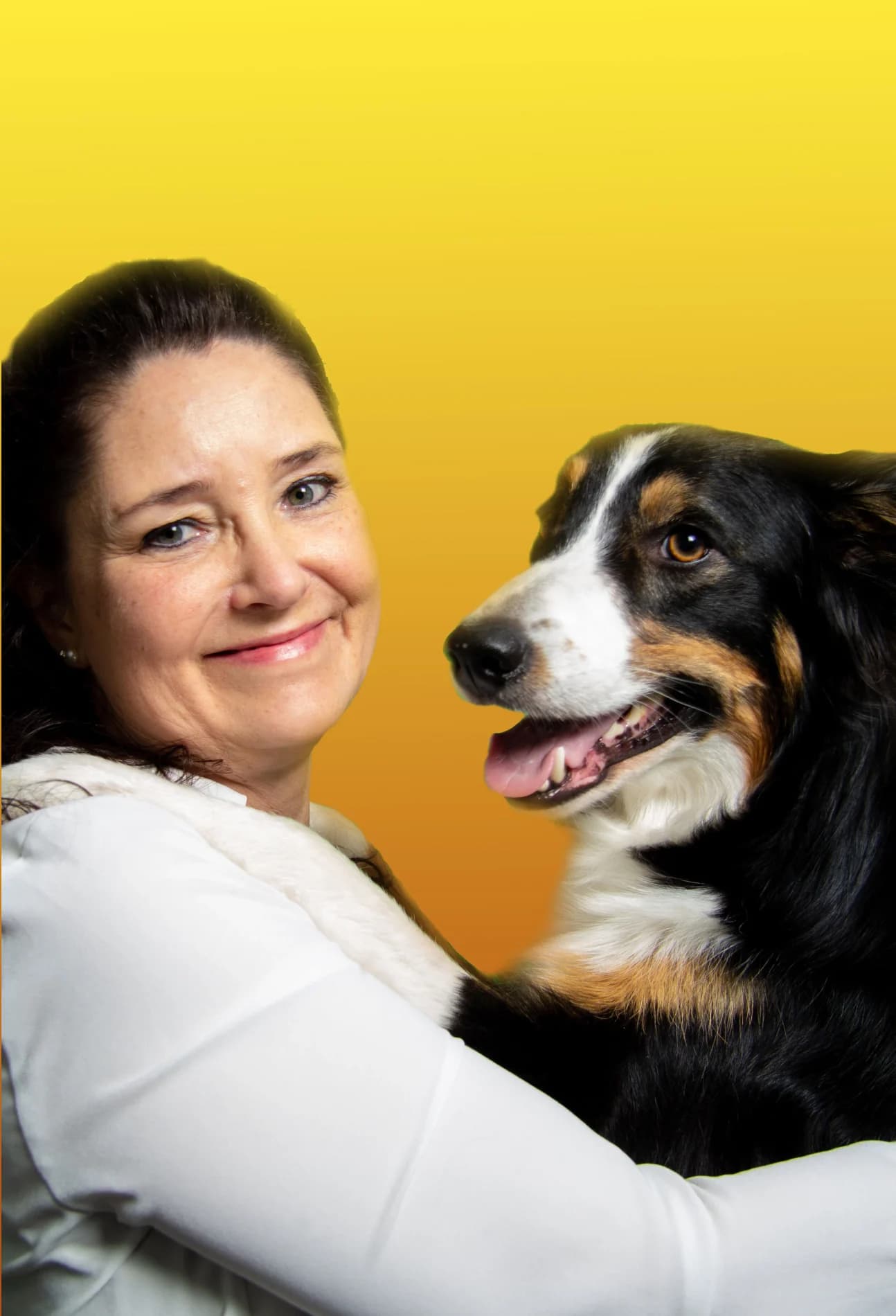 Lizette håller om hunden Lotus som flämtar glatt, båda i närbild mot gul bakgrund